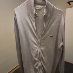  Lacoste tröja helzip  - Tjena, säljer nu min snygga grå kofta från Lacoste då den inte kommer till användning. Använt 2-3 månader men  är i mycket bra skick, ny pris cirka 1700kr.  Mitt Pris är inte hugget i sten och går att diskutera, hör av dig vid minsta lilla fundering.