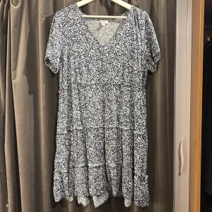 Blå blommig klänning från J.Crew - Säljer en söt blå klänning från J.Crew med ett vitt blommönster. Klänningen har korta ärmar och en v-ringad hals. Perfekt för en avslappnad dag ute. Skriv gärna om eventuella frågor.🌸