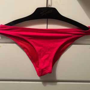 Röd ribbad bikiniunderdel - Snygg röd bikiniunderdel med ribbad struktur. Perfekt för sommarens stranddagar. Enkel och stilren design som passar till många olika överdelar.