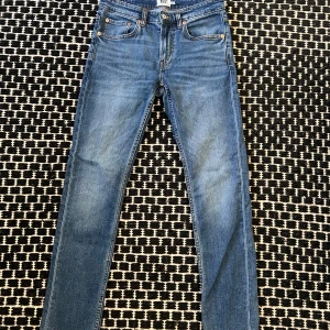 Blå slim jeans från 157 - Snygga blå slim jeans från 157 med klassisk femficksdesign och knappgylf. Perfekta för en stilren look. Midjan är w30 och längden är 32.