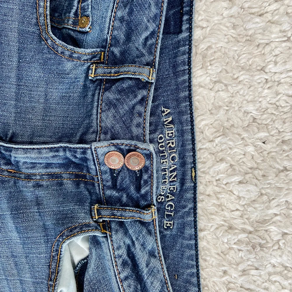 Snygga blå bootcut jeans med klassisk femficksdesign och knappgylf. Perfekta för en avslappnad stil. De har en lätt slitning vid fållen som ger en cool look. Innerbenslängden: 78.5cm och midjemått: 37cm. Farkut & Housut.