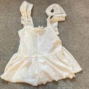 Vit blus från Shein - Säljer en söt vit blus från Shein med broderade detaljer och volanger. Blusen har knytning i ryggen och är ärmlös. Knappt använd men väldigt fin