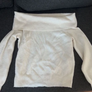 Vit offshoulder tröja - Säljer en stilren vit offshoulder tröja med långa ärmar från Vero Moda men köpt på zalando. Tröjan har en bred ribbad kant vid axlarna och nederkanten, vilket ger en snygg och bekväm passform. 