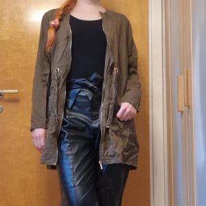 Grön jacka från Zara - Mörkgrön tunn jacka från Zara i strl M. Dragkedja och snörning med guldfärg och fickor fram. Mycket fin och skön som går att stryka 😉 Katt i hemmet. 