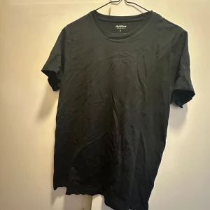 Svart t-shirt från Dobber - Säljer en klassisk svart t-shirt från Dobber i storlek S. Den har en enkel design med rund hals och korta ärmar, perfekt för en stilren look. Gjord i mjukt material för bekväm passform. Perfekt basplagg i garderoben!  Ny pris 249 kr