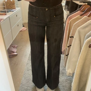 Svarta jeansbyxor med vida ben - Snygga svarta jeansbyxor med vida ben och  mid-waist. Byxorna har unika detaljer vid kedjan och fickorna. W29 men passar även W27/28. De är svarta/gråa. Är öppen för prisförslag, vid funderingar är det bara att skriva till mig💕