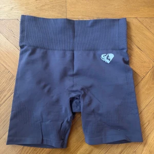 Mörkgrå träningsshorts - Säljer ett par mörkgrå träningsshorts med hög midja och ribbad linning. Har aldrig använt - säljer för att jag har för många träningsbyxor/shorts. Lappen är bortklippt men det är M. 