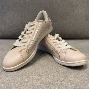 Ljusrosa sneakers med stjärnmönster - Snygga ljusrosa sneakers med små stjärnor och vita snören. Skorna har en glittrig detalj längs sidan och en bekväm passform. Perfekta för en stilren look.