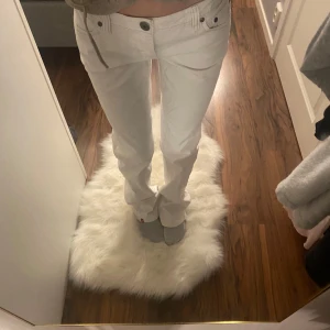 Vita jeansbyxor med låg midja - Snygga vita jeansbyxor med låg midja och raka ben. Byxorna har knappar och dragkedja framtill samt dekorativa sömmar. Perfekta för en stilren look.Passar dig som är 165-180 cm lång.