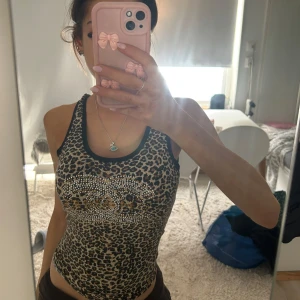 Leopardmönstrad top med strassdetaljer - Snygg leopardmönstrad linne med glittrande strassdetaljer framtill. Köpt utomlands på vintage 