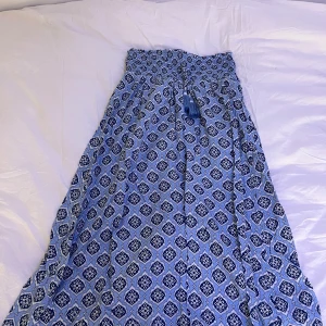 Blå mönstrad långkjol - Snygg blå långkjol med ett detaljerat mönster i vitt och mörkblått. Kjolen har en elastisk midja med knytband och tofsar för extra stil. Perfekt för en avslappnad och chic look. Skriv vid köp:) eller frågor 