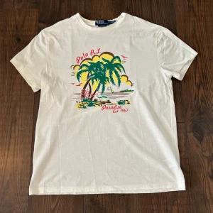 Ralph lauren T-Shirt  - Säljer en vit t-shirt från Polo Ralph Lauren med ett tryck som passar perfekt till sommaren. Nypris runt 1500, Mitt pris 399. Kontakta mig vid eventuella frågor! 