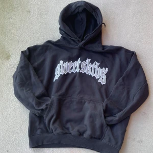 Svart hoodie från Sweet SKTBS (baggy) - Säljer en svart hoodie från Sweet SKTBS med tryck i vitt på framsidan. Den har en klassisk känguruficka och justerbar huva. Perfekt för en avslappnad stil.