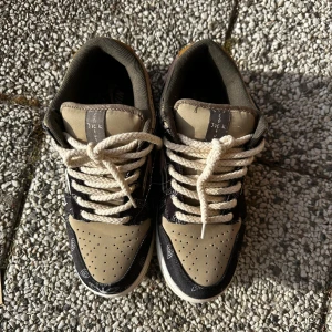 Nike Dunk sneakers med mönster jack cactus 🌵  - Snygga Nike Dunk sneakers i beige och svart med unikt mönster. Skorna har vita snören och en klassisk Nike-logga på hälen. Perfekta för dig som vill ha en stilren men ändå iögonfallande look. Rep