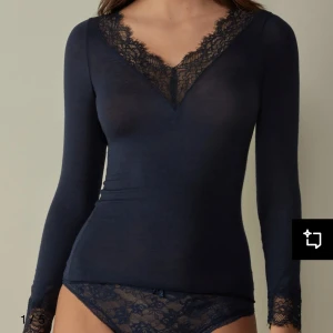 Mörkblå långärmad topp med spetsdetaljer - Elegant mörkblå topp med långa ärmar och v-ringad spetsdetalj. Perfekt för en stilren look.