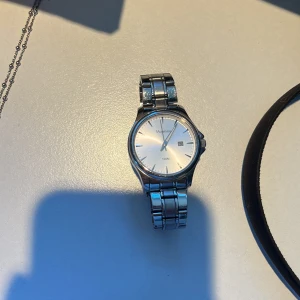 Silverfärgad klocka från Momentum - Snygg och stilren klocka från Momentum i silverfärg. Den har en rund urtavla med datumvisning och ett klassiskt armband i metall. Perfekt för dig som gillar en tidlös design.