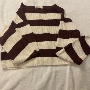 Vinröd och vit randig tröja från H&M - Säljer en snygg vinröd och vit randig tröja från H&M. Tröjan är stickad och har en croppad passform med långa ärmar. Perfekt för en avslappnad stil.