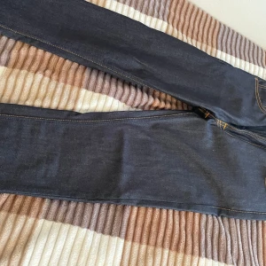 Mörkblå jeans från Nudie Jeans - Snygga mörkblå jeans från Nudie Jeans i ekologisk bomull. De har en klassisk femficksdesign med orange kontrastsömmar och en dragkedja. Perfekta för en stilren look. Pris kan diskuteras. Slim fit