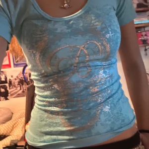 Ljusblå t-shirt med glittrigt tryck - Snygg ljusblå t-shirt från Elite med korta ärmar och glittrigt, silvrigt tryck framtill. Omsydd för att sitta tightare. Öppen för att förhandla priset🥰🥰
