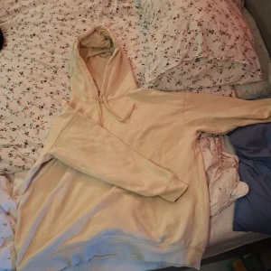 Beige hoodie från H&M med huva - Säljer en beige hoodie från H&M i storlek M. Tröjan har en klassisk huva med snörning och långa ärmar. Materialet är mjuk bomull och passformen är normal. Perfekt för chill dagar eller när du vill ha något bekvämt och enkelt.