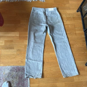 Ljusgrå raka jeans från Zara - Snygga ljusgrå jeans från Zara med rak passform och klassisk femficksdesign. Jeansen har råa kanter vid bensluten för en cool och avslappnad vibe. Tillverkade i bomull med en mjuk jeanskänsla. Perfekta för dig som gillar stilrena och enkla jeans.