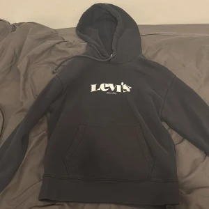 Svart hoodie från Levi's med logga - Svart hoodie från Levi's i storlek S med stor vit logga på bröstet. Tröjan har huva med snörning och en klassisk magficka framtill. mycket bra skick