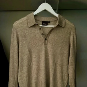 Beige pikétröja från Oscar Jakobsson - Snygg beige pikétröja från Oscar Jakobsson i mjukt material. Tröjan har klassisk krage, knappar framtill och långa ärmar. Använd fåtal gånger, nypris 1799