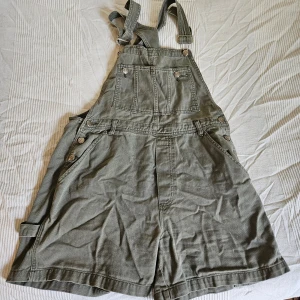 Overallshorts olivgröna - Coola overallshorts med många fickor. Tips: använd bälteslooparna för att matcha med ett snyggt skärp! (Pris kan diskuteras vid köp av flera varor)