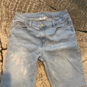 Ljusblå jeansshorts från D.M.D - Snygga ljusblå jeansshorts från D.M.D med klassisk femficksdesign och knappgylf. Modellen är midwaist och har raka ben som slutar strax ovanför knäna. Perfekt för dig som gillar en chill och enkel stil under varma dagar.