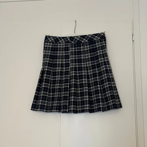 Mörkblå rutig kortkjol - En mörkblå rutig kjol med en liten dragkedja och knapp. Har aldrig används.(lappen är dock inte kvar). Inte stretchigt material. 