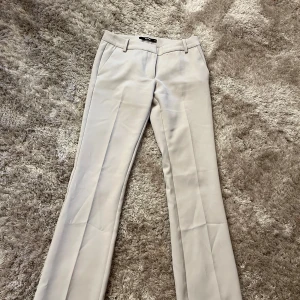Beige kostymbyxor med bootcut - Snygga beige kostymbyxor med bootcut, low waist. Använda 1 gång, väldigt sköna