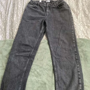 Grå jeans Street Loose från Grunt - Säljer ett par grå jeans från Grunt, modellen Street Loose. De har en loose passform med raka ben och klassiska fem fickor. Jeansen är tillverkade i denim och har en cool, mörkgrå tvätt som ger en avslappnad vibe. Perfekta för dig som gillar streetstil.