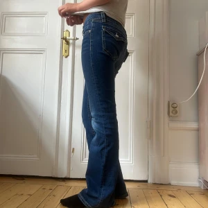 Bootcut jeans från Gina, blå - True Religion liknande blå bootcut jeans från Gina Young i storlek 158  Jeansen har låg midja och är tillverkade i mjukt denim med lite stretch för skön passform. Använda ganska mycket men inga defekter. Lite slitna där nere men inte så mycket att trådarna hänger ut så det syns inte 💓💓 Perfekta till hösten eftersom de är väldigt mjuka och sköna🍂