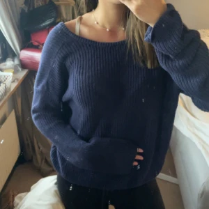 Mörkblå stickad tröja med v-ringad rygg - Mysig mörkblå stickad tröja med bred v-ringning både fram och bak. Tröjan har lång ärm och en loose passform som ger en avslappnad vibe. Perfekt att slänga på sig över ett linne eller topp för en chill look.