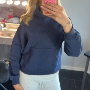 Mörkblå hoodie  - Mörkblå hoodie från Gina med klassisk huva. Hoodien har ribbade muddar vid ärmslut och nederkant, samt en relaxed passform. Perfekt för chill dagar eller när du vill ha en enkel och stilren look. Är använd men är i nytt skick.