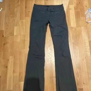 lowwaisted kostymbyxor bootcut - Snygga mörkgrå kostymbyxor med bootcut och dubbla knappar framtill. Byxorna har klassisk passform och är perfekta för en stilren look. Tillverkade i ett mjukt tyg som känns bekvämt hela dagen.