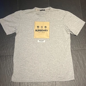 Grå Burberry t-shirt med logga - Snygg grå t-shirt från Burberry. Burberrys logga och texten 'London England'. Perfekt för dig som gillar stilrena designer och exklusiva märken. 