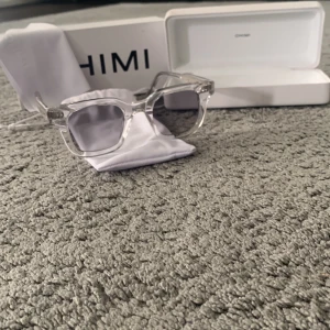  glasögon från CHIMI - Snygga glasögon från CHIMI med transparent båge och fyrkantig form. Kommer med vit förvaringsask och putsduk. Perfekt för dig som gillar stilrena och moderna accessoarer. Bågen är i plast och har en cool, minimalistisk vibe.