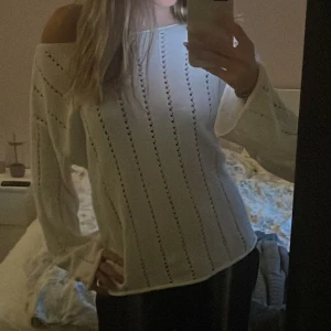 Vit stickad långärmad tröja - Säljer en vit stickad tröja med lång ärm och snygga hålstickade ränder. Tröjan har en klassisk passform och är perfekt för lager-på-lager. Superfin till både jeans och kjol för en fräsch look.