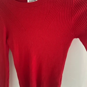 Röd ribbad tröja från Kappahl - Snygg röd ribbstickad tröja från Kappahl med lång ärm och rund halsringning. Tröjan har coola ribbade detaljer som ger en modern look. Perfekt att styla med jeans eller kjol för en trendig outfit. 