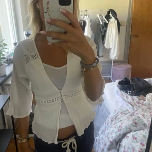 Vit omlottkofta med spetsdetaljer - Säljer en superfin vit omlottkofta med trekvartsärm och snygga spetsdetaljer vid axlar och midja. Tyvärr så är det ett litet hål upptill men inget som är jätte märkvärt. Även lätt att fixa!❤️
