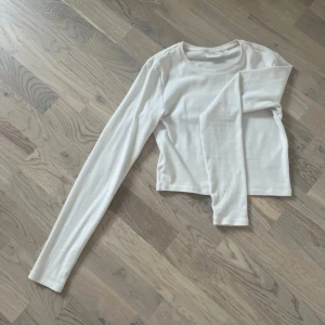 Vit långärmad topp från Gina Tricot - Enkel och stilren vit långärmad topp från Gina Tricot. Modellen är rak med rund halsringning och är tillverkad i mjuk bomull. Perfekt att matcha med jeans eller kjol för en clean look. Är en magtröja💗