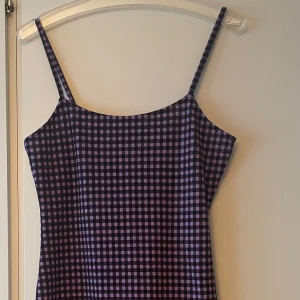 *NY*Lila och svart rutig klänning H&M stl M  - Supersöt kort klänning från H&M med smala axelband och rutigt mönster i lila och svart. Figurnära passform och tillverkad i mjuk polyester med lite stretch. Perfekt för dig som gillar en trendig och lekfull stil. Uppskattar att den passar 36/38 då modellen är mindre i stl. Retrovibe.