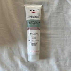 Eucerin DermoPurifyer Oil Control - Eucerin DermoPurifyer Oil Control Triple Effect Cleansing Gel är en ansiktsrengöring för fet och aknebenägen hud. Tuben är vit med detaljer i grönt och vinrött, och innehåller en gel som motverkar blemmor, märken och glans.