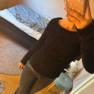 Svart fluffig långärmad tröja - Mysig svart långärmad tröja med fluffig och lurvig textur. Tröjan har en rund halsringning och sitter snyggt med en normal passform. 