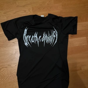 Svart Breathe Divinity compression - Svart t-shirt med stort vitt tryck i metallstil på bröstet från Breathe Divinity. Klassisk passform med rund hals och korta ärmar. Perfekt för dig som gillar bandmerch och streetwear.