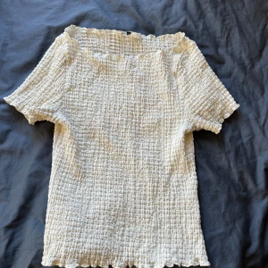 Vit smockad topp med kort ärm - Vit/beige topp från hm. Tyvärr är lappen borta men skulle gissa på att storleken är mellan xs och s. Skriv om ni önskar bild med tröjan på. Pris kan diskuteras!