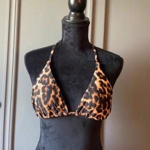 Leopardmönstrad bikiniöverdel - Snygg trekantsbikini med leopardmönster. Klassisk modell med knyt i nacken och ryggen för perfekt passform. Den är helt ny utan prislapp. 