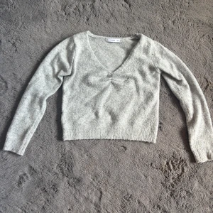 Ljusgrå stickad v-ringad tröja MNG - Supermjuk ljusgrå stickad tröja från MNG med v-ringning och lång ärm. Tröjan har en lätt croppad passform och ribbade muddar. Perfekt för lager-på-lager och chill vibes. Den har en minimal defekt som ej syns när man har på sig den. Se bild 💖