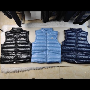 Moncler Väst - Säljer glansig dunväst från Moncler med hög krage och två dragkedjefickor framtill. Västen har quiltad design och klassisk Moncler-logga på bröstet. Perfekt för lager-på-lager och riktigt snygg till streetwear.